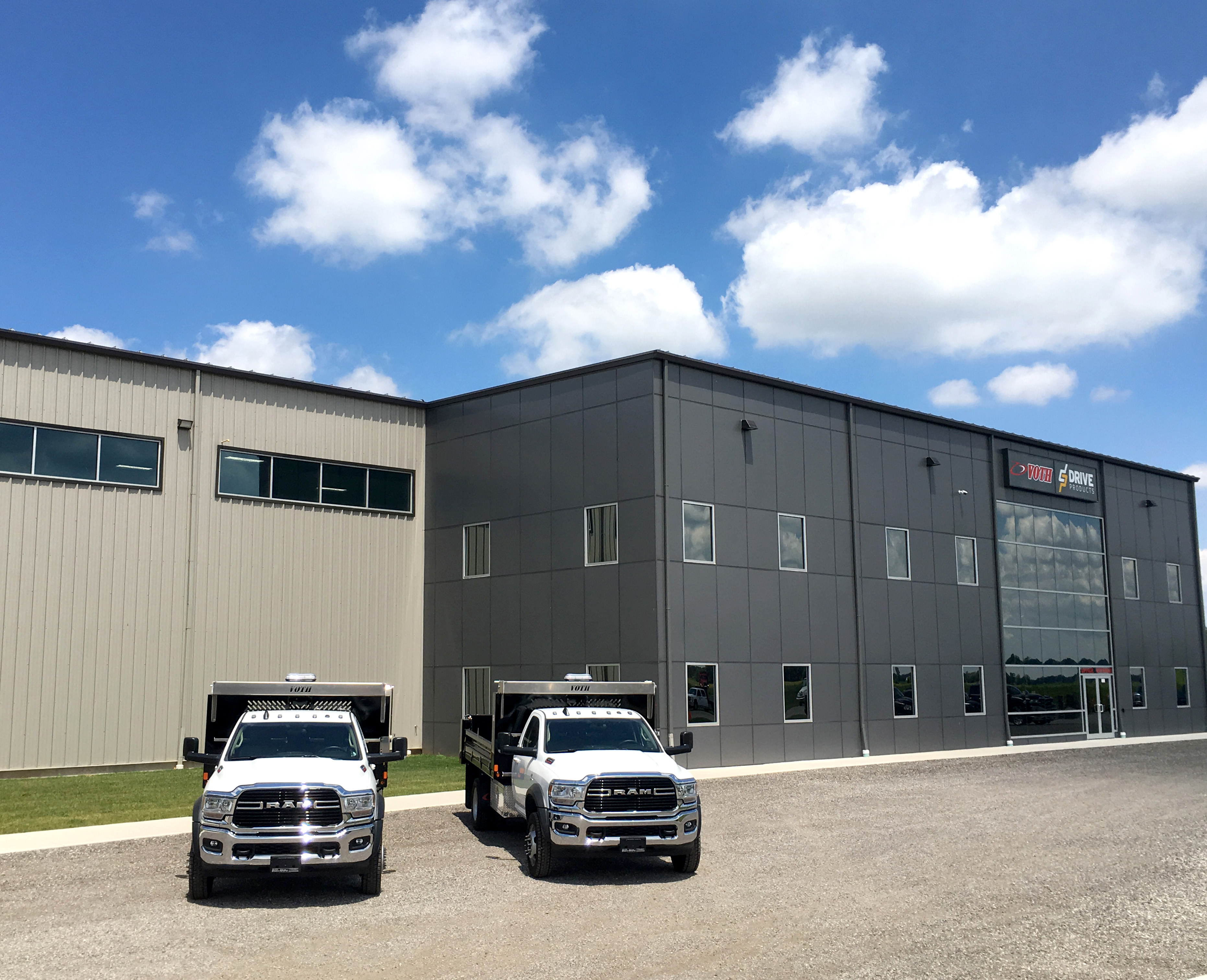 two trucks in front of a large manufacturing and office space branded with Drive Products and Voth 